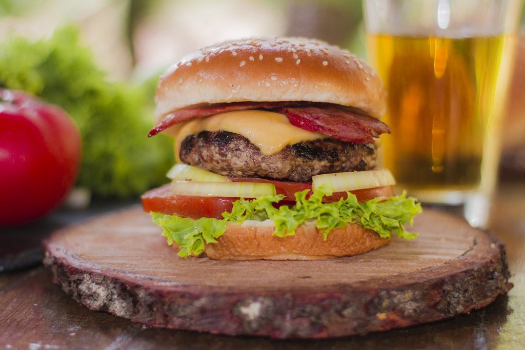 Hamburger mit Bacon auf Holzbrett.