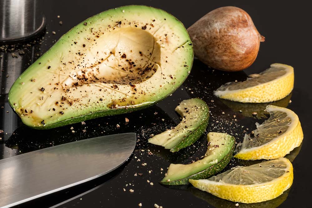 Aufgeschnittene Avocado, daneben Zitrone und ein Messer