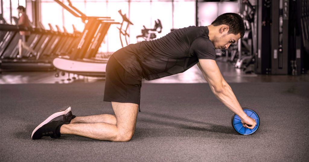 Mann führt Sit Ups Alternative Bauchroller am Boden aus.