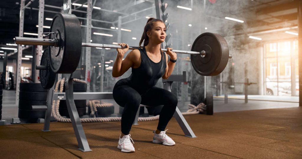 Junge Frau macht Squats im Fitnessstudio