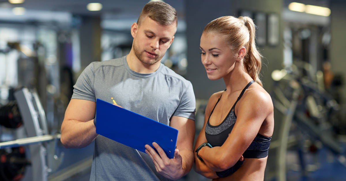 Mann und Frau planen Trainingsfrequenz im Fitnessstudio